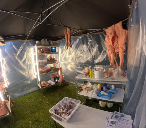 Interior view of AwithA Body Shop with silicone body casts, workshop table, shelves and CRT monitors, Lapinlahti Film Festival, Helsinki, 2026.